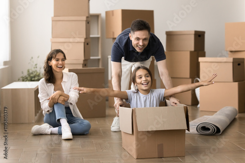 Funny excited family playing on relocation day, daddy push cardboard box with seated inside little daughter, take break, enjoy playtime during relocation day to new house, exuding happiness and joy