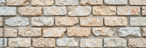 Beige stone brick wall with rough texture and natural patterns
