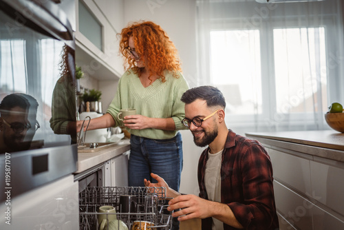 girlfriend help boyfriend to put dishes in dishwasher in kitchen