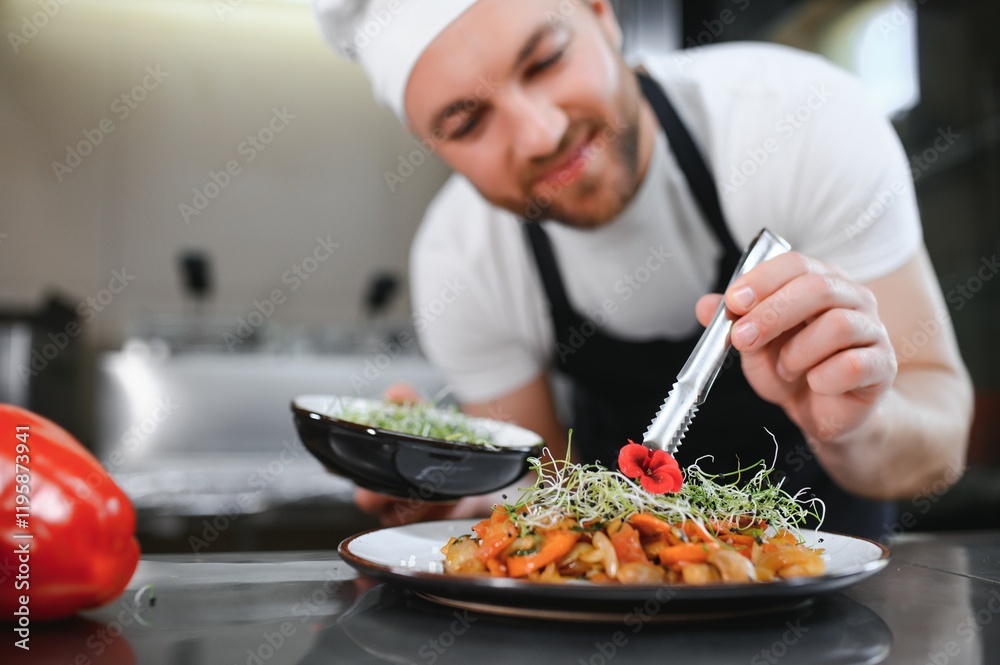 Naklejka premium Closeup of a concentrated male chef garnishing food in the kitchen