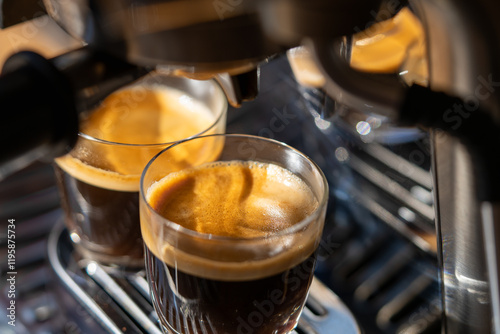 Картината върху платно Closeup of two glasses of freshly brewed espresso coffee with crema made by an e