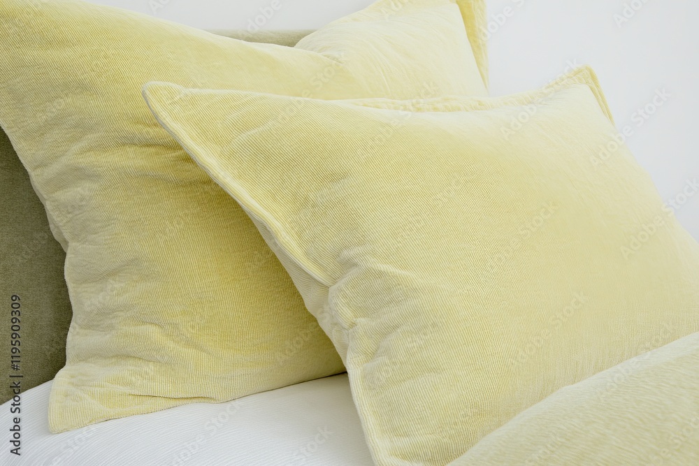 Obraz premium A yellow pillow is on top of a white pillow. The pillows are fluffy and soft, giving off a cozy and comfortable vibe