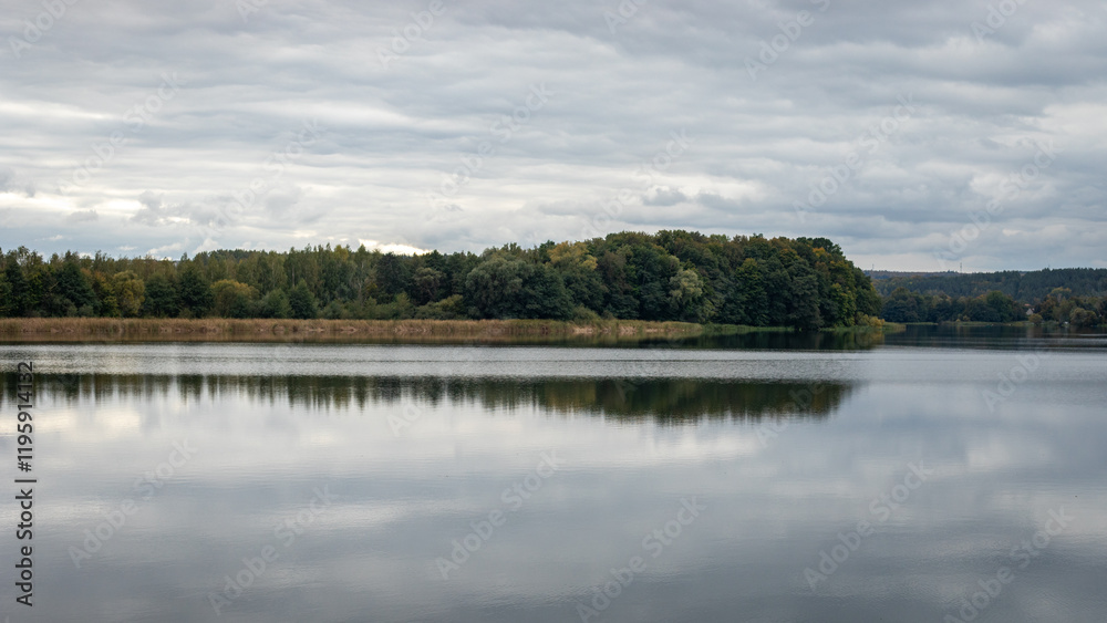 Fototapeta premium Peaceful lake with forest reflections under cloudy sky