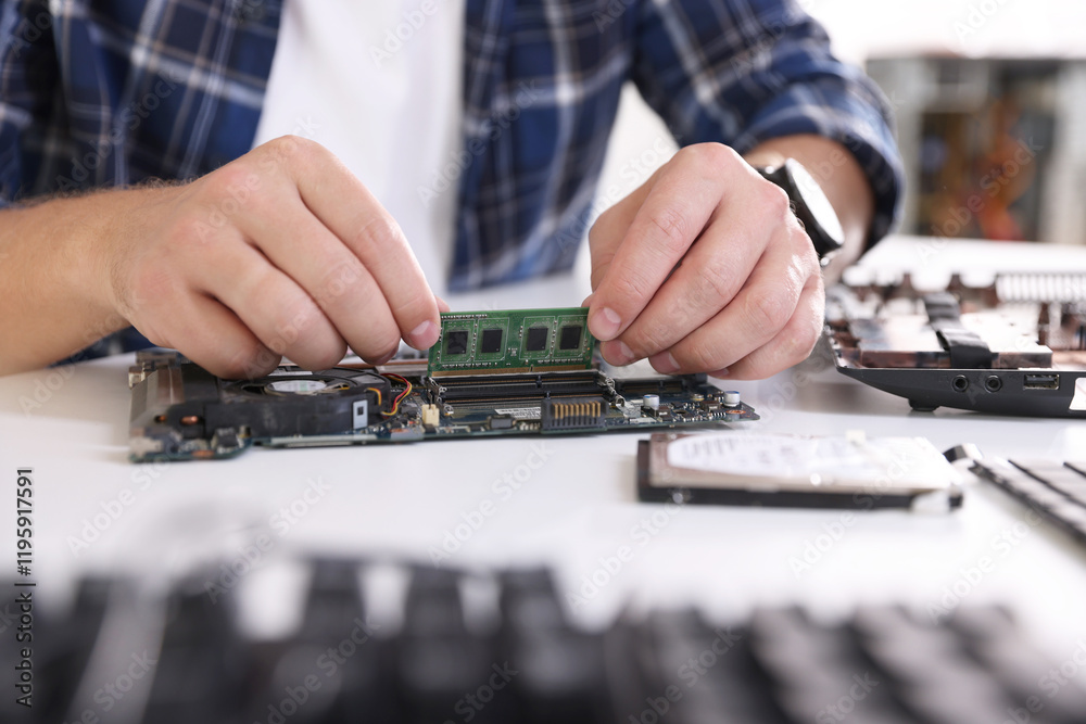 Fototapeta premium Man installing computer chip onto motherboard at white table, closeup