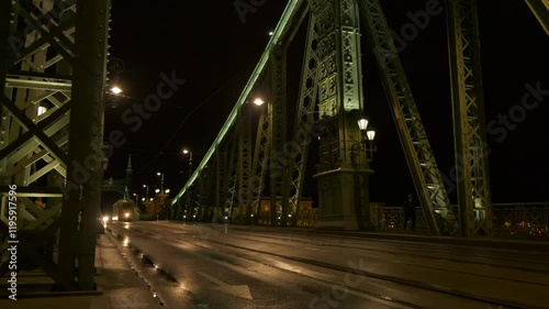 Typical tram on bridge at night. A view of public tramway crossing the green bridge during night time in Budapest.