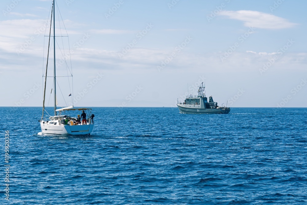 A small sailboat with three individuals is being inspected by an armed forces vessel in the open sea, showcasing maritime security operations and the importance of safeguarding waters. A small sailboat with three individuals is being inspected by an armed forces vessel in the open sea, showcasing maritime security operations and the importance of safeguarding waters.