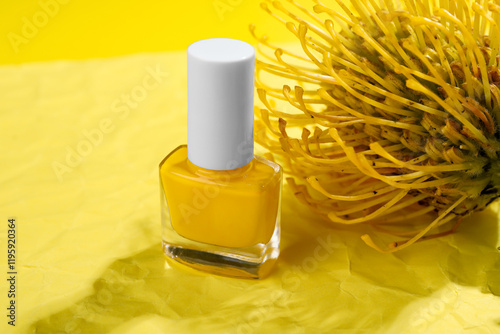 Nail polish in bottle and flower on yellow background, closeup photo