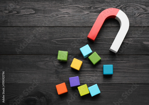 Magnet attracting colorful cubes on wooden table, flat lay. Space for text