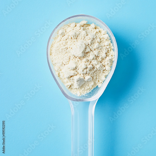 Scoop of powder in a plastic spoon with light blue background photo