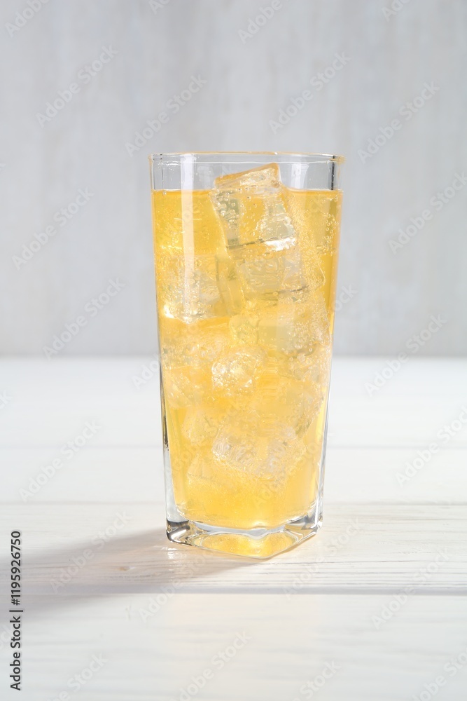 Sweet soda water with ice cubes in glass on white wooden table Sweet soda water with ice cubes in glass on white wooden table
