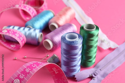 Different sewing supplies on pink background, closeup
