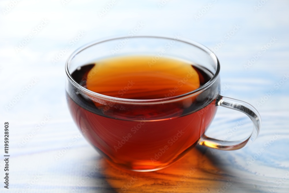 Aromatic black tea in cup on light blue wooden table, closeup Aromatic black tea in cup on light blue wooden table, closeup