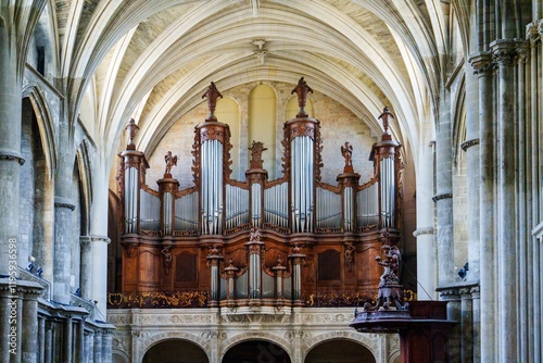 The grand organ, adorned with exquisite carvings and multiple golden pipes, stands majestically in the church, enhancing the architectural beauty of the vaulted ceiling and the overall ambiance. photo