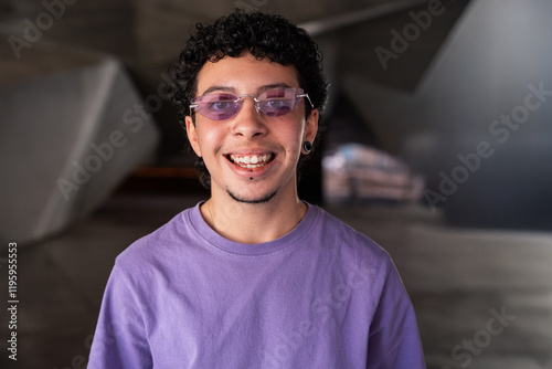 Transgender person smiling confidently wearing purple shirt and tinted glasses photo