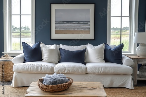 coastal living room with white slipcovered sofa navy blue accent pillows driftwood coffee table and oversized black and white beach photography photo