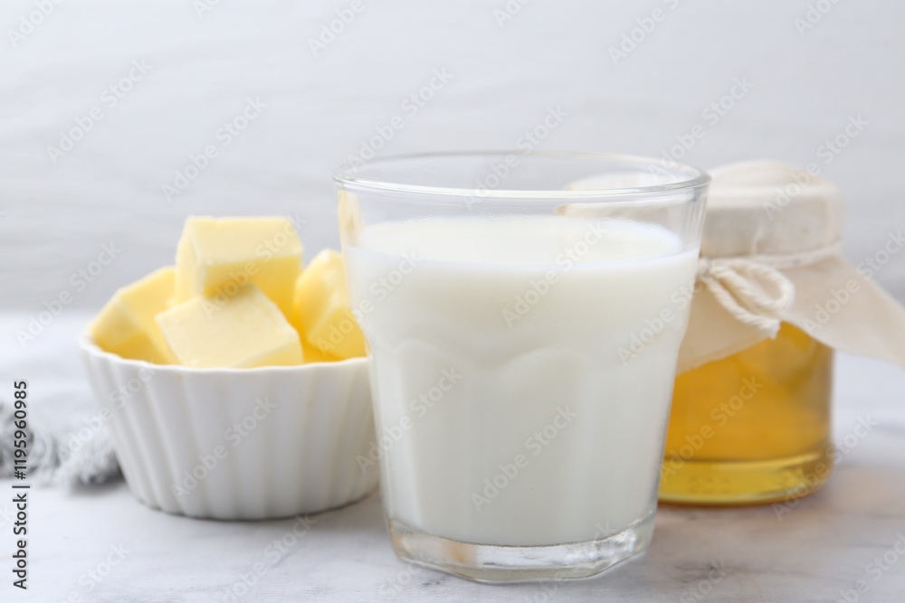 Fresh milk in glass, honey and butter on white marble table, closeup Fresh milk in glass, honey and butter on white marble table, closeup