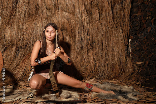 Young beautiful native American woman sitting on the animal skin and holding huge kukri knife photo