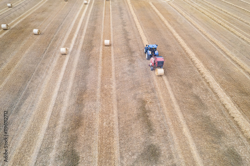 Nupaky, Czech republic - July 10, 2024. Aerial view of tractor making straw bales photo