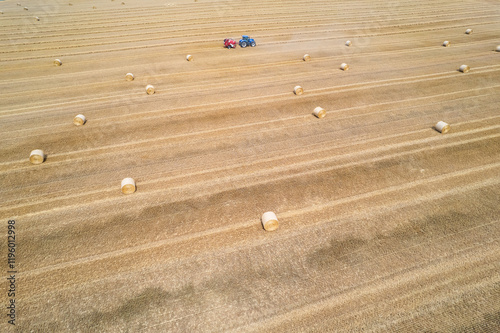 Nupaky, Czech republic - July 10, 2024. Aerial view of tractor making straw bales photo