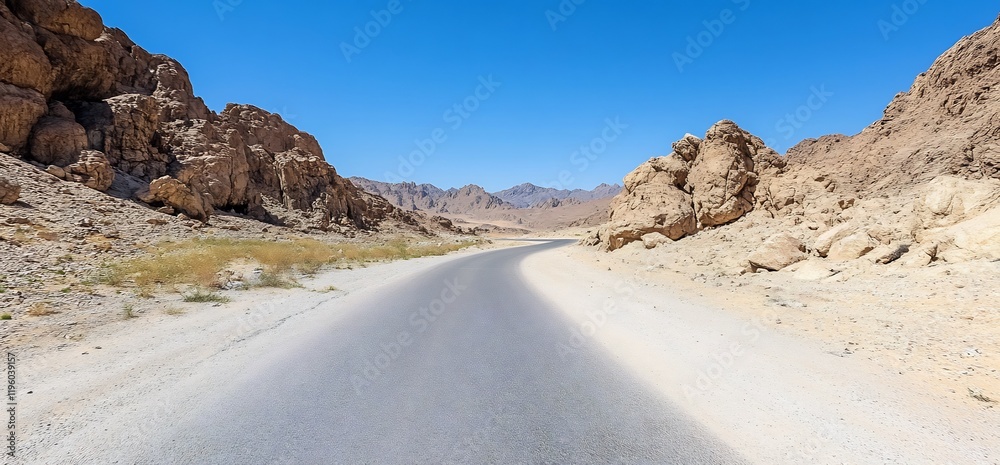 Desert road winding through rocky mountains under a clear blue sky. Travel background Desert road winding through rocky mountains under a clear blue sky. Travel background