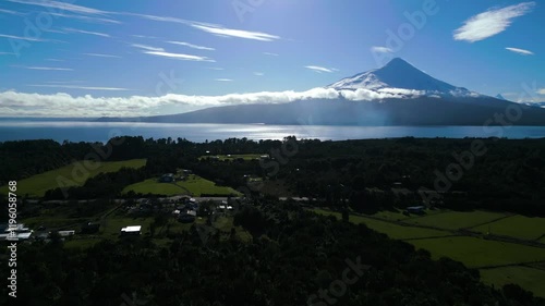 Aerial View of Snow-Capped Volcano and Serene Lake with Green Fields