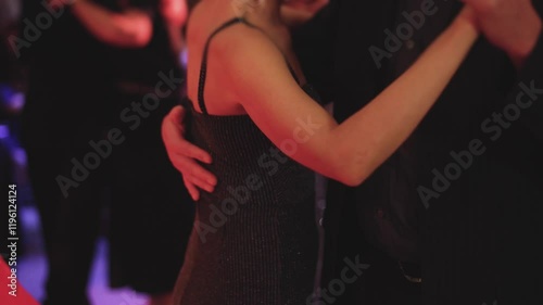 Couples dancing traditional latin argentinian dance milonga in the ballroom, tango salsa bachata kizomba lesson in red and purple lights, evening dance school class festival, performance rehearsal
