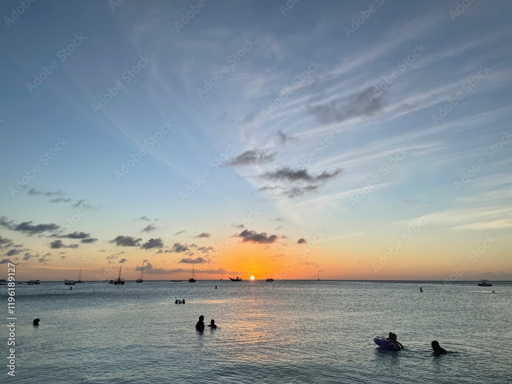 Fototapeta premium Sunset over a serene beach with silhouetted figures