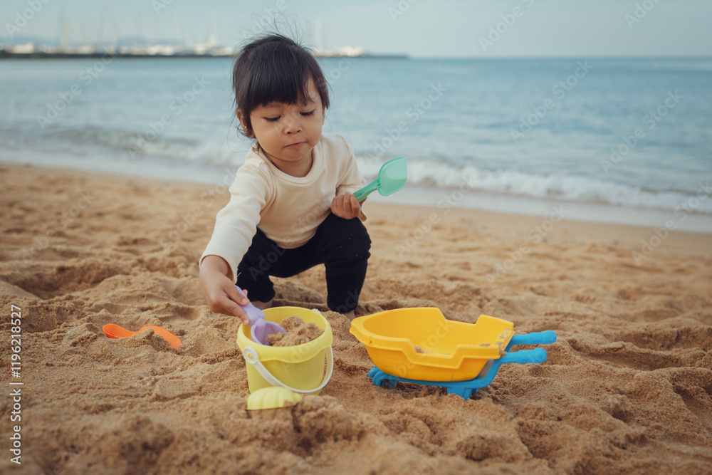 toddler baby girl playing sand toy on sea beach in Pattaya, Thailand toddler baby girl playing sand toy on sea beach in Pattaya, Thailand