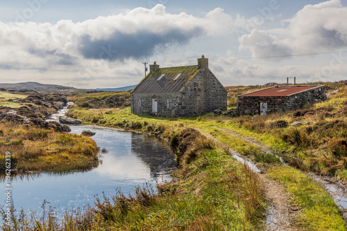 Scotland, Hebrides. Isle of North Uist. Traditional stone house by a stream. Moorland. photo