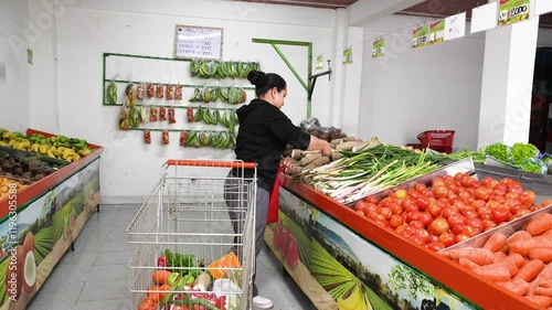 A housewife is choosing onions to take home, in a market cart while walking