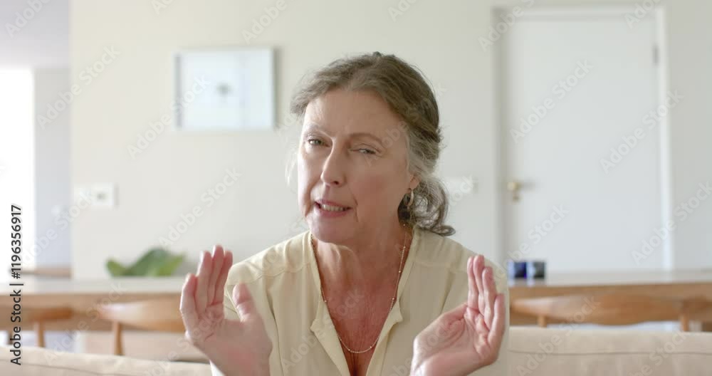 Senior woman sitting on sofa, expressing discomfort or pain at home Senior woman sitting on sofa, expressing discomfort or pain at home