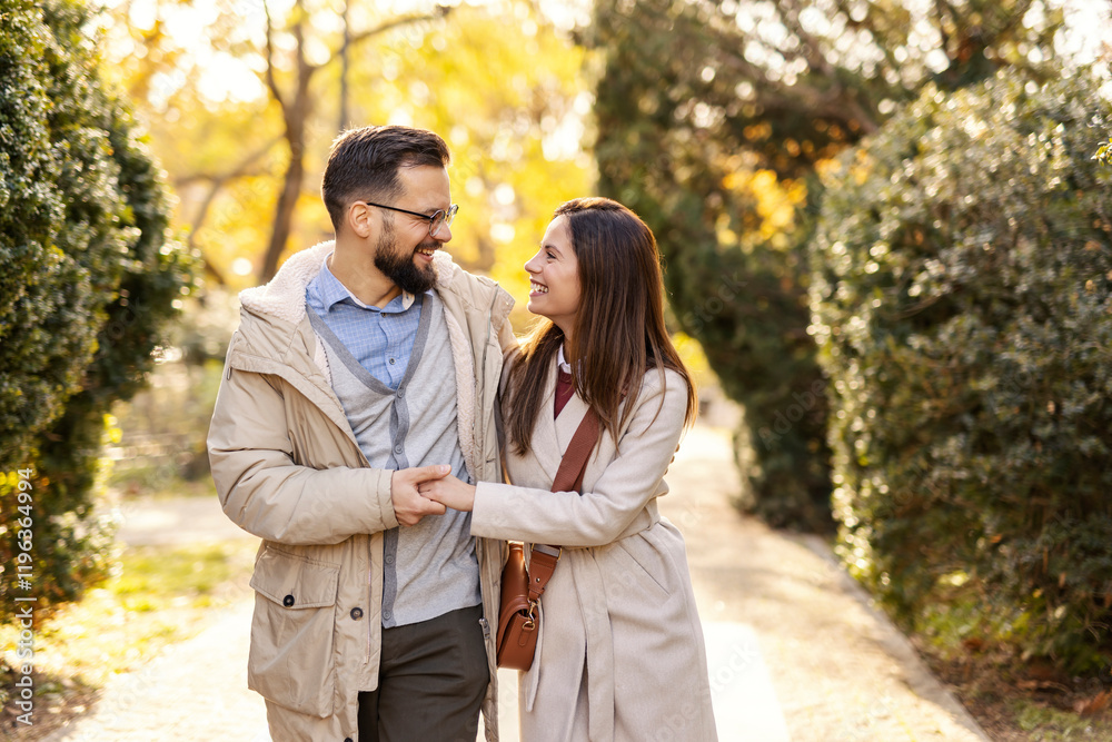 Young romantic couple in love hugging and talking a walk in park while smiling at each other. Young romantic couple in love hugging and talking a walk in park while smiling at each other.