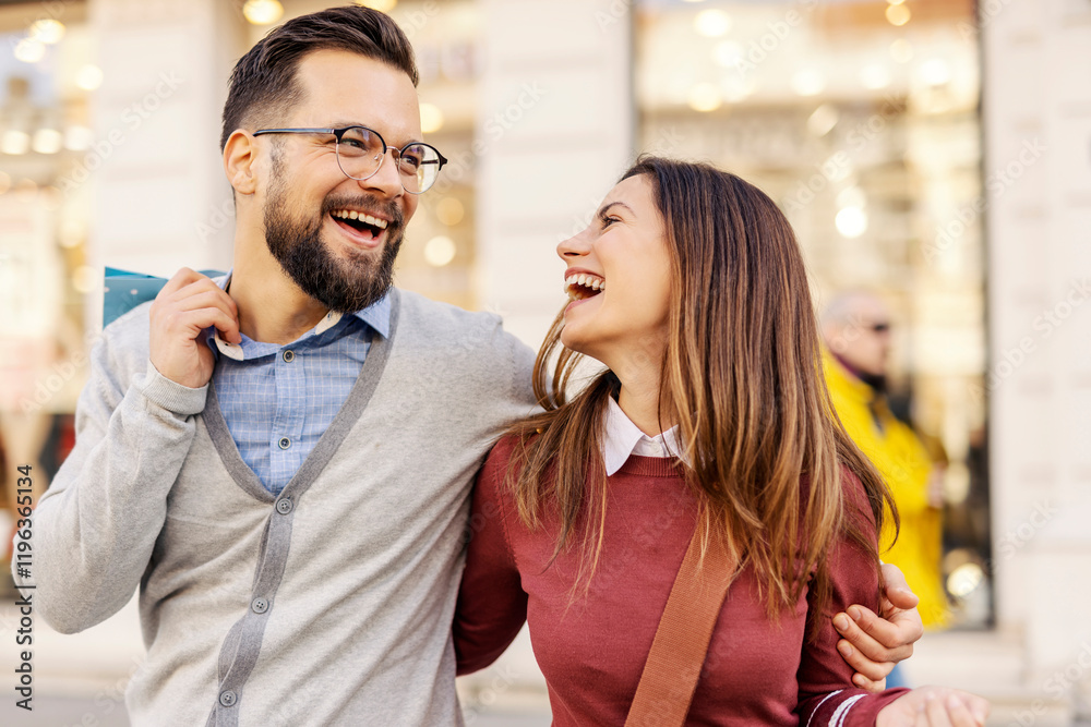 Naklejka premium Young romantic couple hugging and smiling on city street with shopping bags in hands.