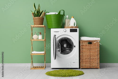Modern washing machine with rack, baskets and detergents near green wall
