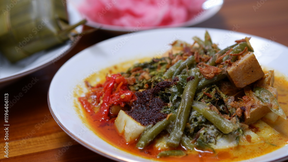 Ketupat Sayur Padang or Vegetable Padang rice cake with jackfruit vegetables, coconut milk sauce, rendang seasoning and crackers. Indonesia food. Ketupat Sayur Padang or Vegetable Padang rice cake with jackfruit vegetables, coconut milk sauce, rendang seasoning and crackers. Indonesia food.