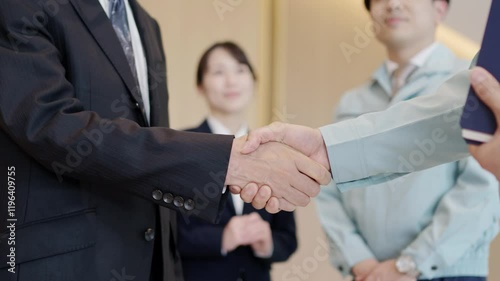 握手をするビジネスマンと作業服を着た男性