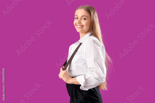 Stylish young woman with suspenders on purple background
