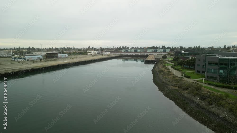 Aerial view of the Encinal Basin at Mariner Square in Alameda, California, showcasing calm waters surrounded by marinas and urban landscapes. Aerial view of the Encinal Basin at Mariner Square in Alameda, California, showcasing calm waters surrounded by marinas and urban landscapes.