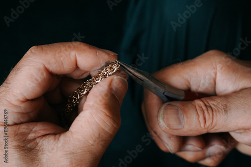 Jeweler making a chain of rings. Close up of the hands of a goldsmith. Concept: jewelry, gold, fashion. Horizontal photo