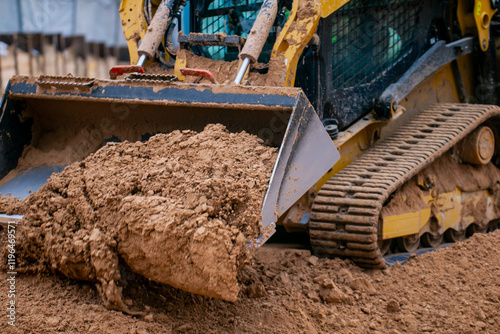 Track compact loader working in construction project leveling the ground and excavating materials for preparation of building project photo