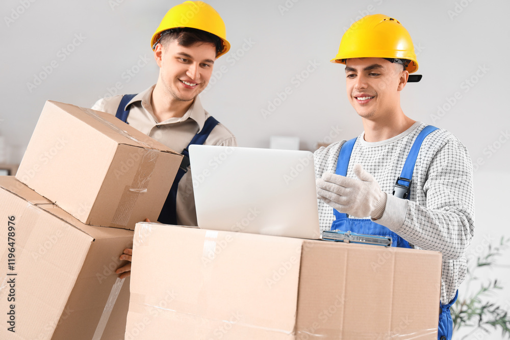 Male loaders working with laptop and boxes in office Male loaders working with laptop and boxes in office