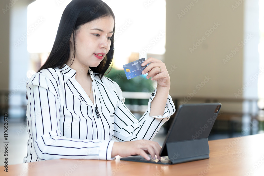 Woman holding credit card while shopping online on tablet Woman holding credit card while shopping online on tablet