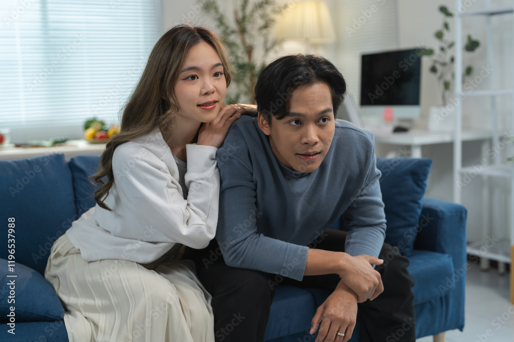 Happy young asian couple relaxing together on a comfortable sofa, enjoying a cozy evening while watching television in their inviting living room, cherishing quality time and connection Happy young asian couple relaxing together on a comfortable sofa, enjoying a cozy evening while watching television in their inviting living room, cherishing quality time and connection