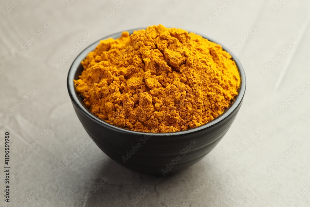 Turmeric powder in bowl on grey table, closeup Turmeric powder in bowl on grey table, closeup