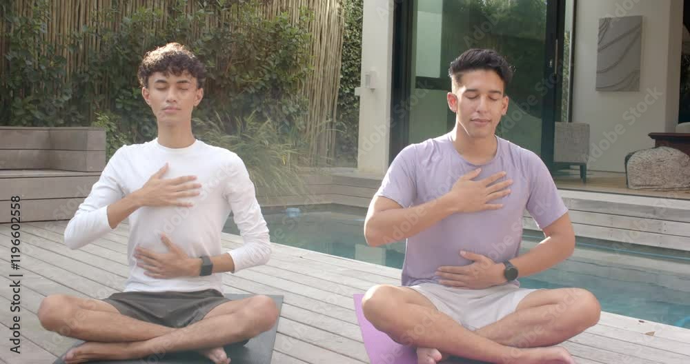 Meditating outdoors, multiracial gay couple practicing mindfulness on yoga mats by pool Meditating outdoors, multiracial gay couple practicing mindfulness on yoga mats by pool