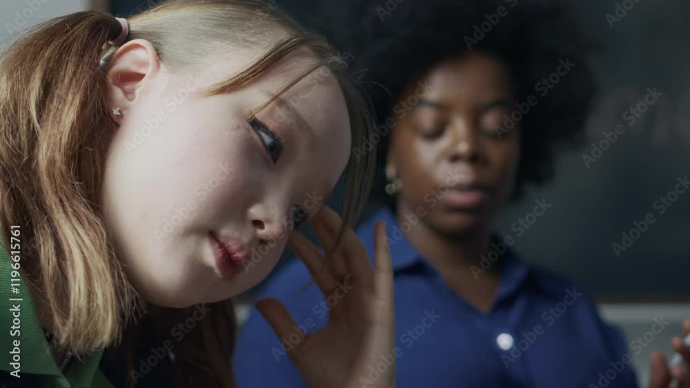 Close up shot of rebellious Asian teen girl turning away from young Black female psychologist talking to her and asking questions during individual therapy consultation in class Close up shot of rebellious Asian teen girl turning away from young Black female psychologist talking to her and asking questions during individual therapy consultation in class