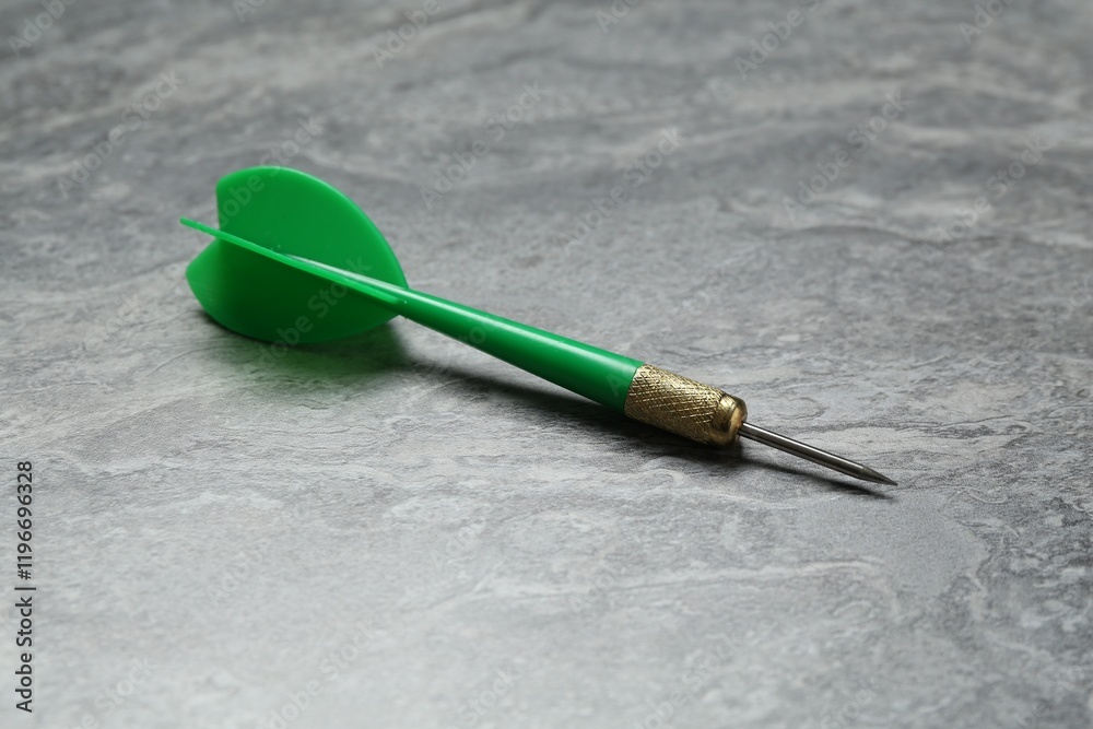One green dart arrow on grey textured table, closeup One green dart arrow on grey textured table, closeup