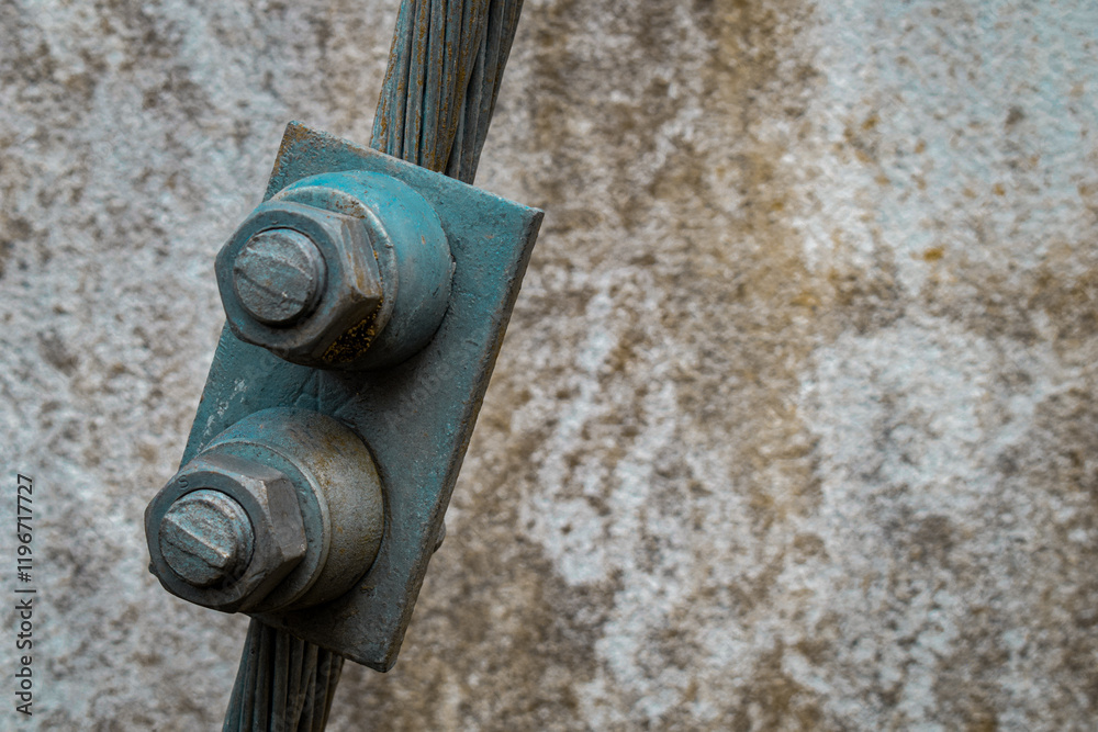 The image captures the contrast between the smooth metal of the bolt and the textured insulation of the wire. The image captures the contrast between the smooth metal of the bolt and the textured insulation of the wire.