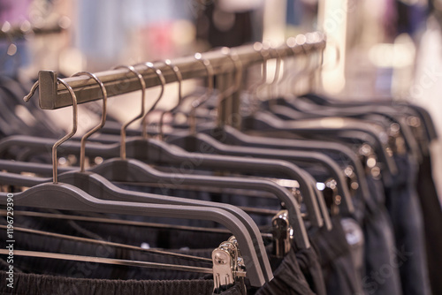 Close up of clothing rack with black pants on hangers in boutique store display. photo