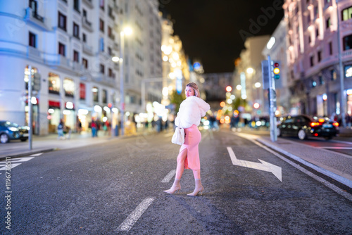 Fashionable woman crossing the street in gran via, madrid, at night